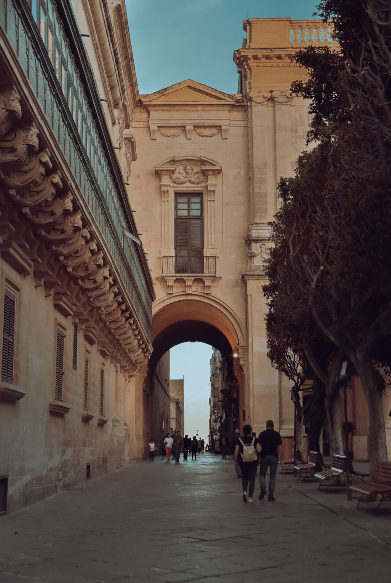 Pedestrians walking a colonnaded street in Valletta, Malta